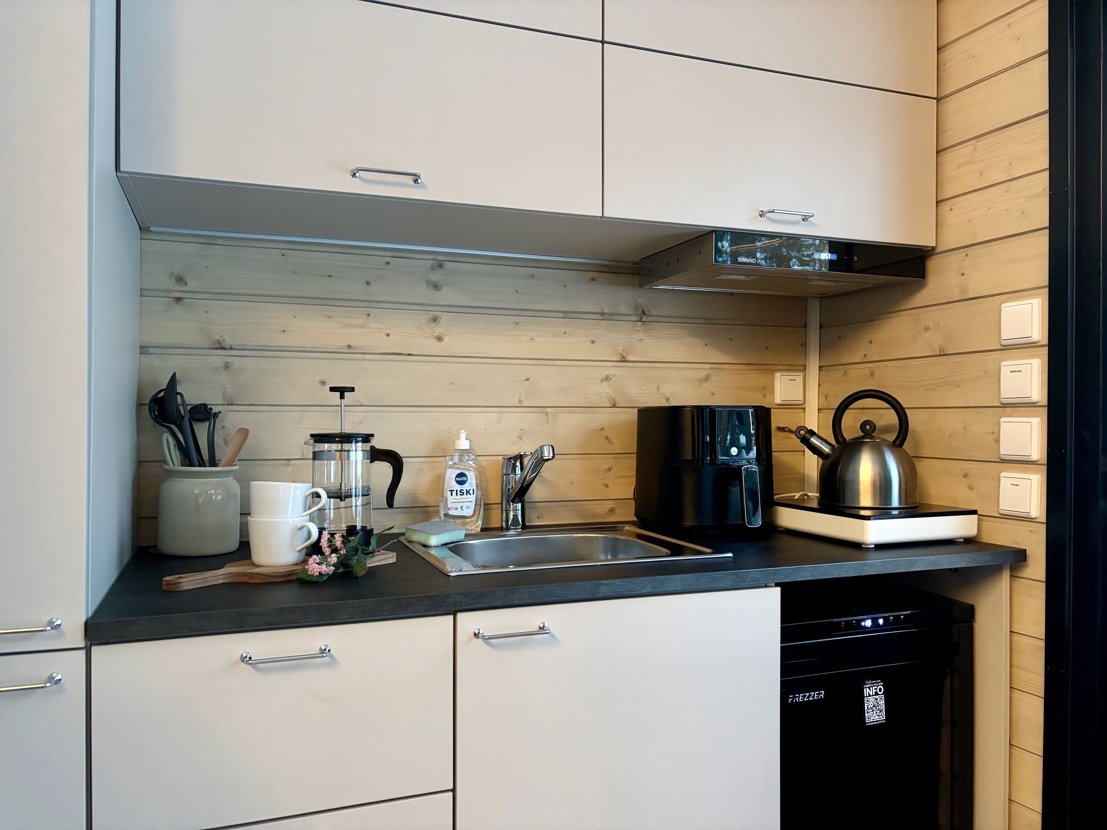 A modern kitchen with a coffee maker, kettle, and dishwasher.