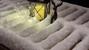 A snow-covered table with a lantern and a reindeer decoration.