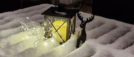 A snow-covered table with a lantern and a reindeer decoration.
