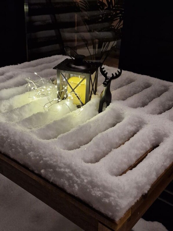 A snow-covered table with a lantern and a reindeer decoration.