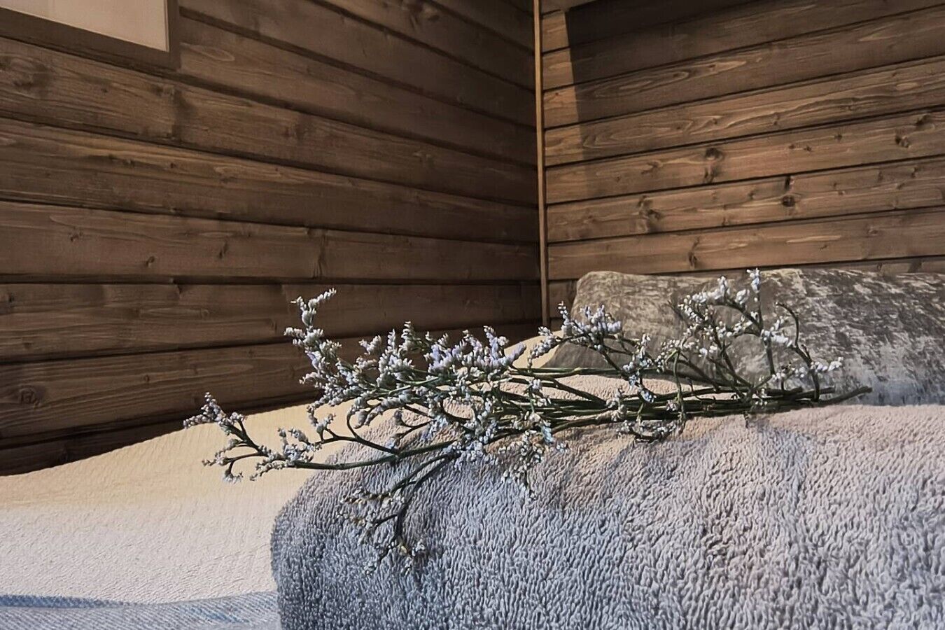 A room with wooden walls and a bed with a textured blanket.