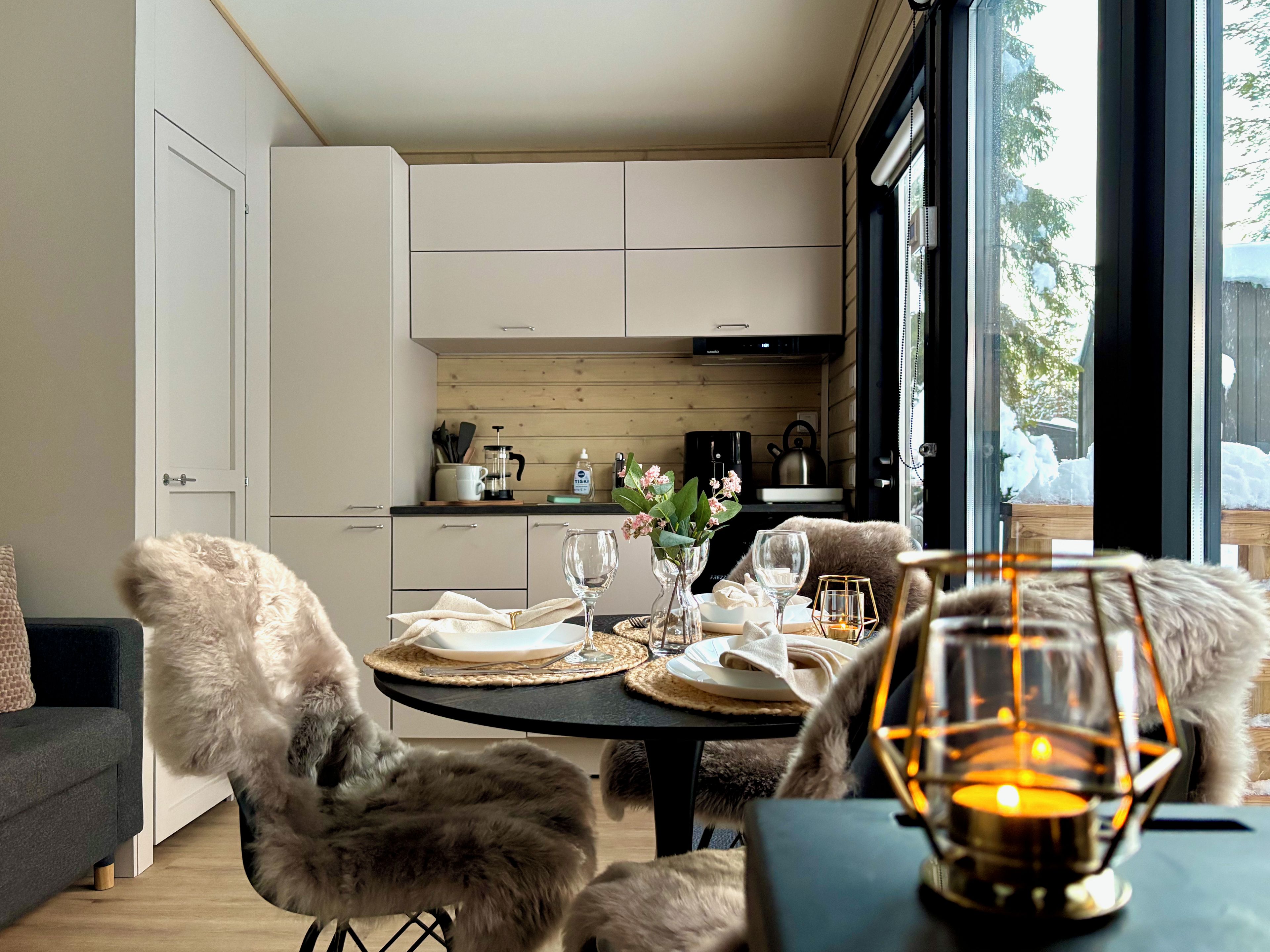 Un comedor acogedor con una mesa lista para dos, una butaca con funda de piel y una vela en un candelabro de cristal.