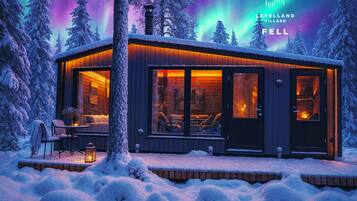 A cozy cabin with a wooden exterior, large windows, and a fireplace visible through the windows.