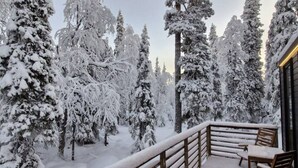 A snow-covered balcony with wooden railings and a table and chairs.