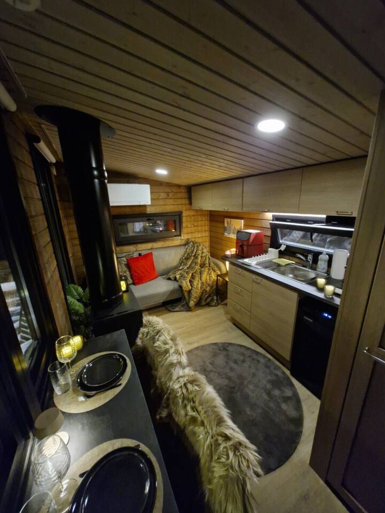 Et kompakt køkken med spiseplads, en hund og et spisebord dækket til to personer.