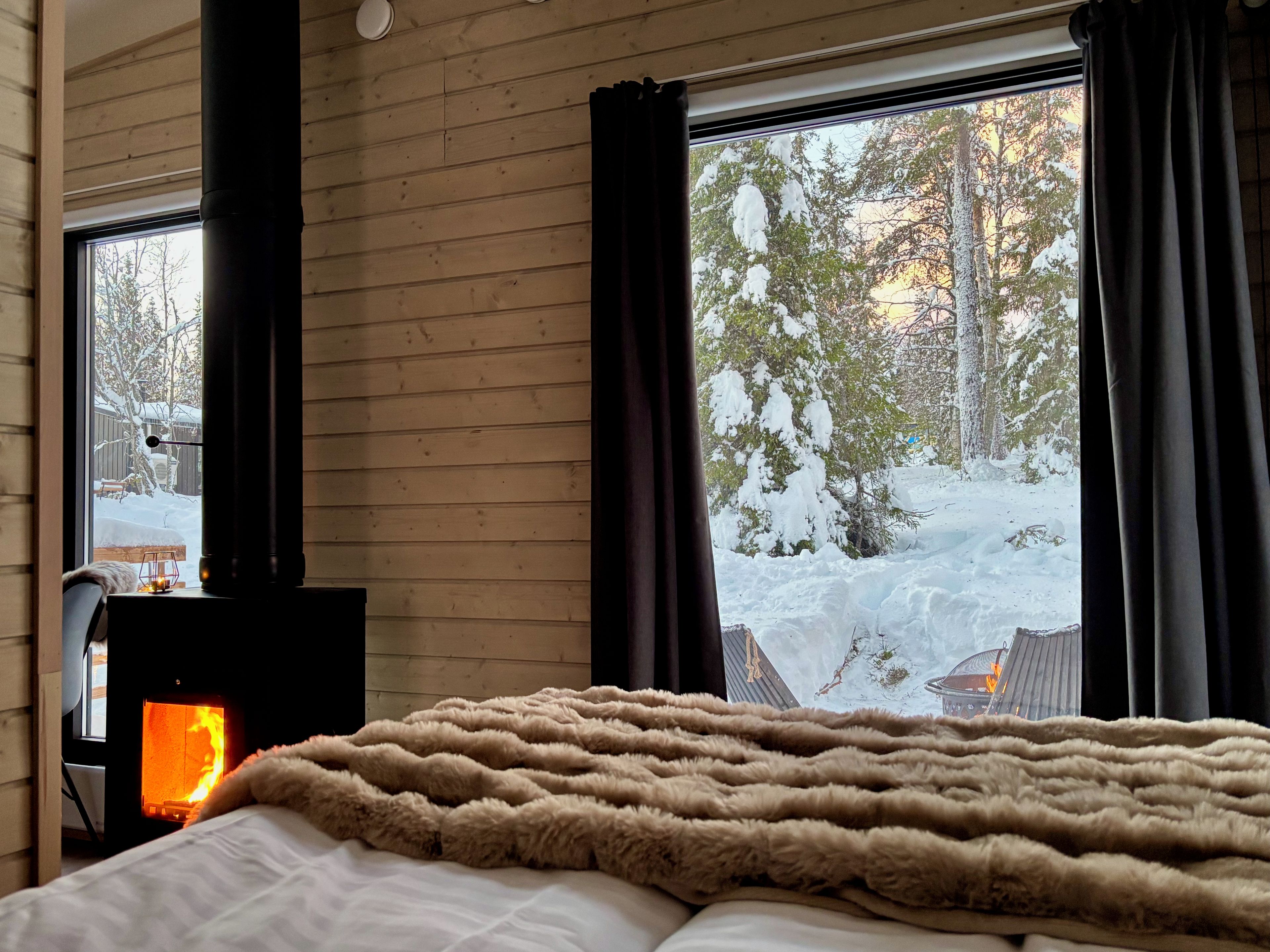 A room with a bed, a fireplace, and a window with curtains.