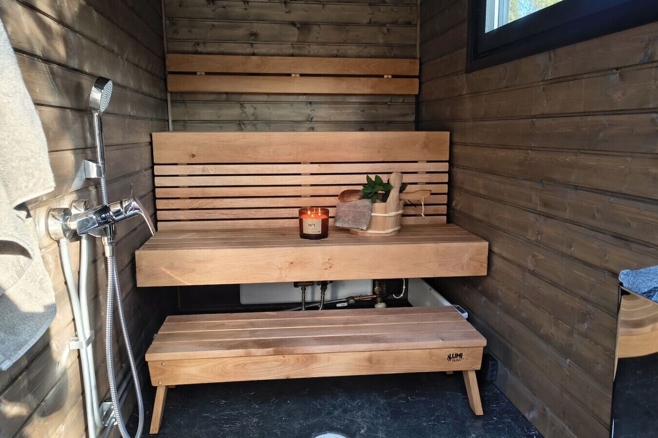 A wooden bench with a candle and a wooden container, likely for holding items.