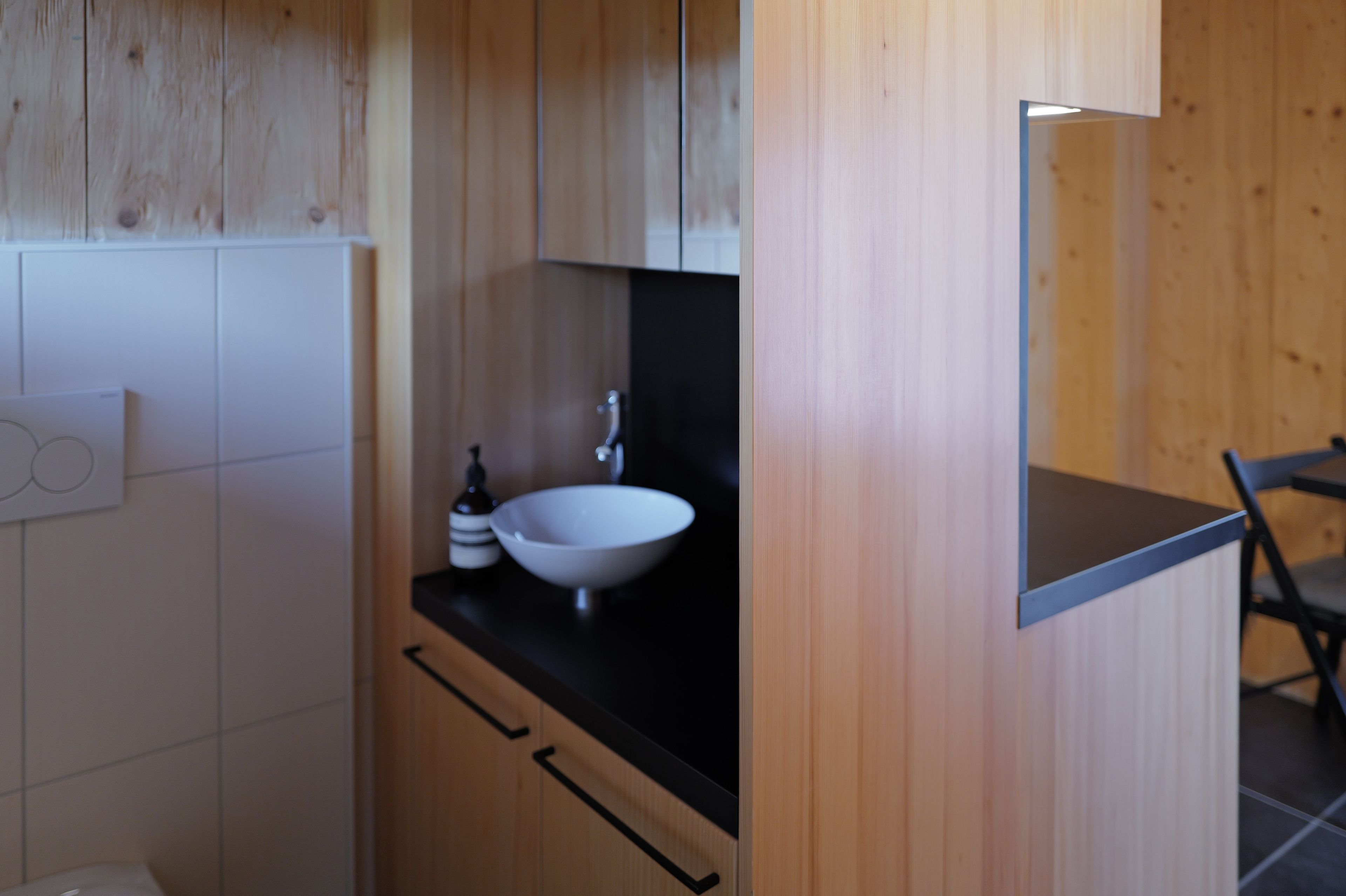 Ein modernes Badezimmer mit einem Holzlagerflächen, einem weißen Waschbecken und einer schwarzen Arbeitsplatte.