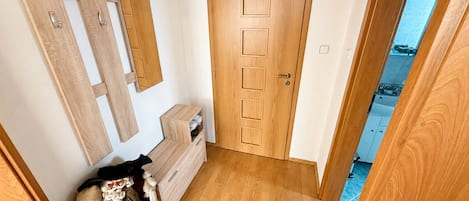 Una puerta de madera con manija, un mueble pequeño de madera con cajones y un espejo en la pared.