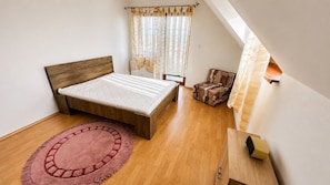 A bedroom with a bed, a chair, a radiator, and a window with curtains. - 2 room Apartment, mountains view, Stará Lesná (Stará Lesná)
