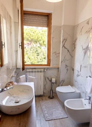Ein Badezimmer mit einem großen, ovalen Waschbecken, einer Toilette und einer Badewanne.