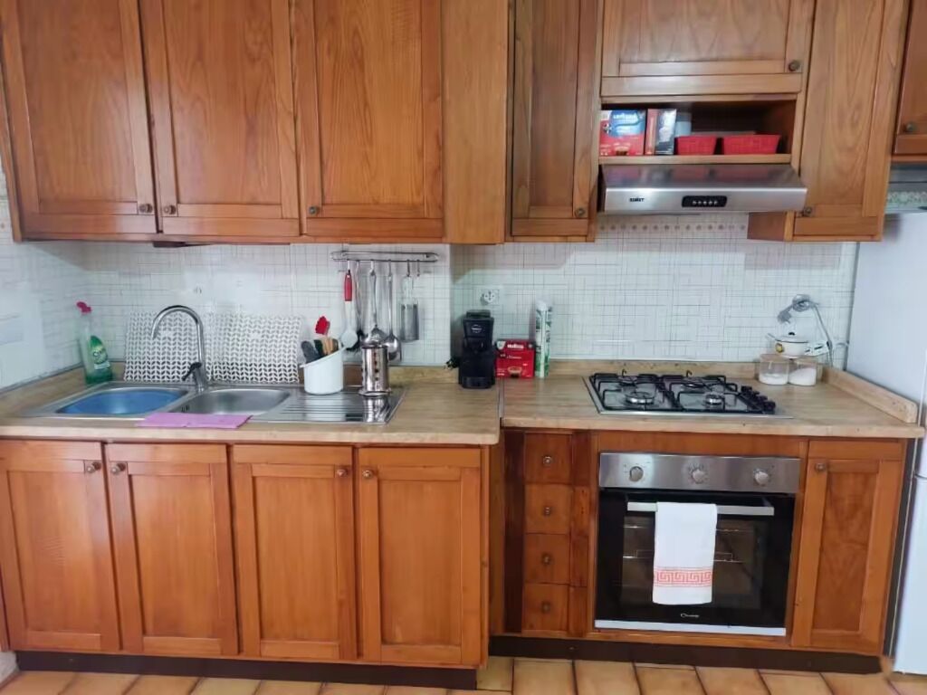 A kitchen with wooden cabinets, a stainless steel sink, a gas stove, and an oven.