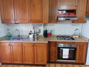 Eine Küche mit Holzausstattung, einer Edelstahlspüle, einem Gasherd und einem Backofen.