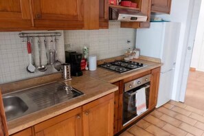 Cuina amb armaris de fusta, rentamicroones d'acer inoxidable, fogó a gas i forn integrat.