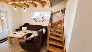 Un salon chaleureux avec un canapé marron, une table basse en bois et un escalier en bois.