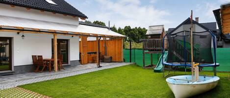 A backyard with a covered patio, a boat, and a slide.