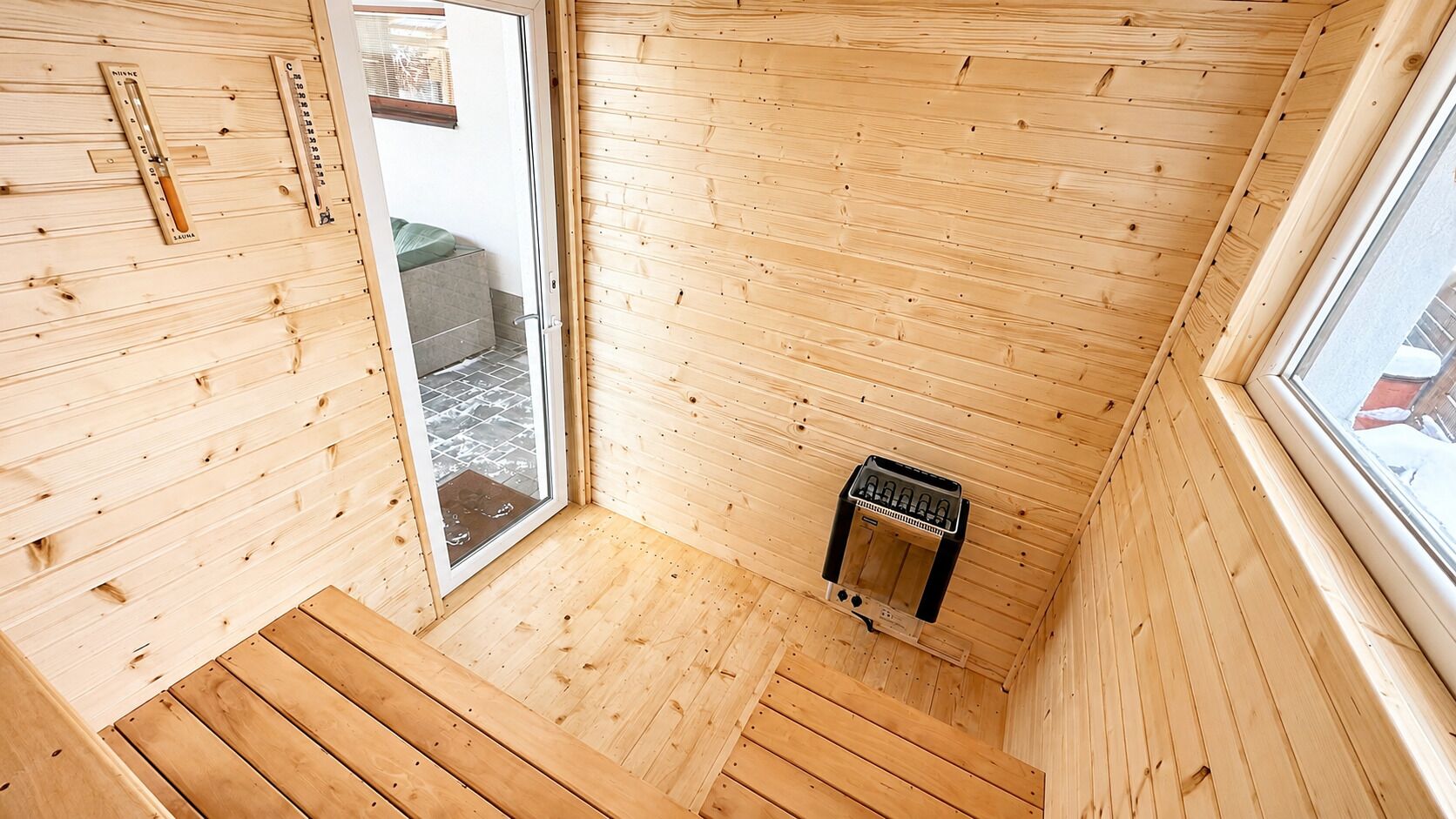 A wooden interior with a sauna, a window, and a door leading outside.