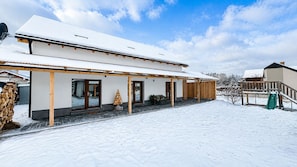 A snow-covered building with a covered porch and a green slide. - Apartment house, sauna and jacuzzi, Svätý Kríž 1 (Svätý Kríž)