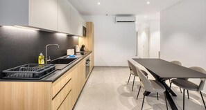 A modern kitchen with a central island, a dining table with chairs, and a built-in air conditioning unit. - Designer Msida Suite | Balcony & Private Terrace (L-Imsida)
