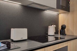 A modern kitchen with a built-in induction cooktop, a coffee maker, and a kettle. - Designer Msida Suite | Balcony & Private Terrace (L-Imsida)