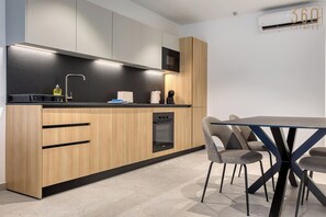 A modern kitchen with a built-in oven, microwave, and a dining area with a table and chairs. - Designer Msida Suite | Balcony & Private Terrace (L-Imsida)