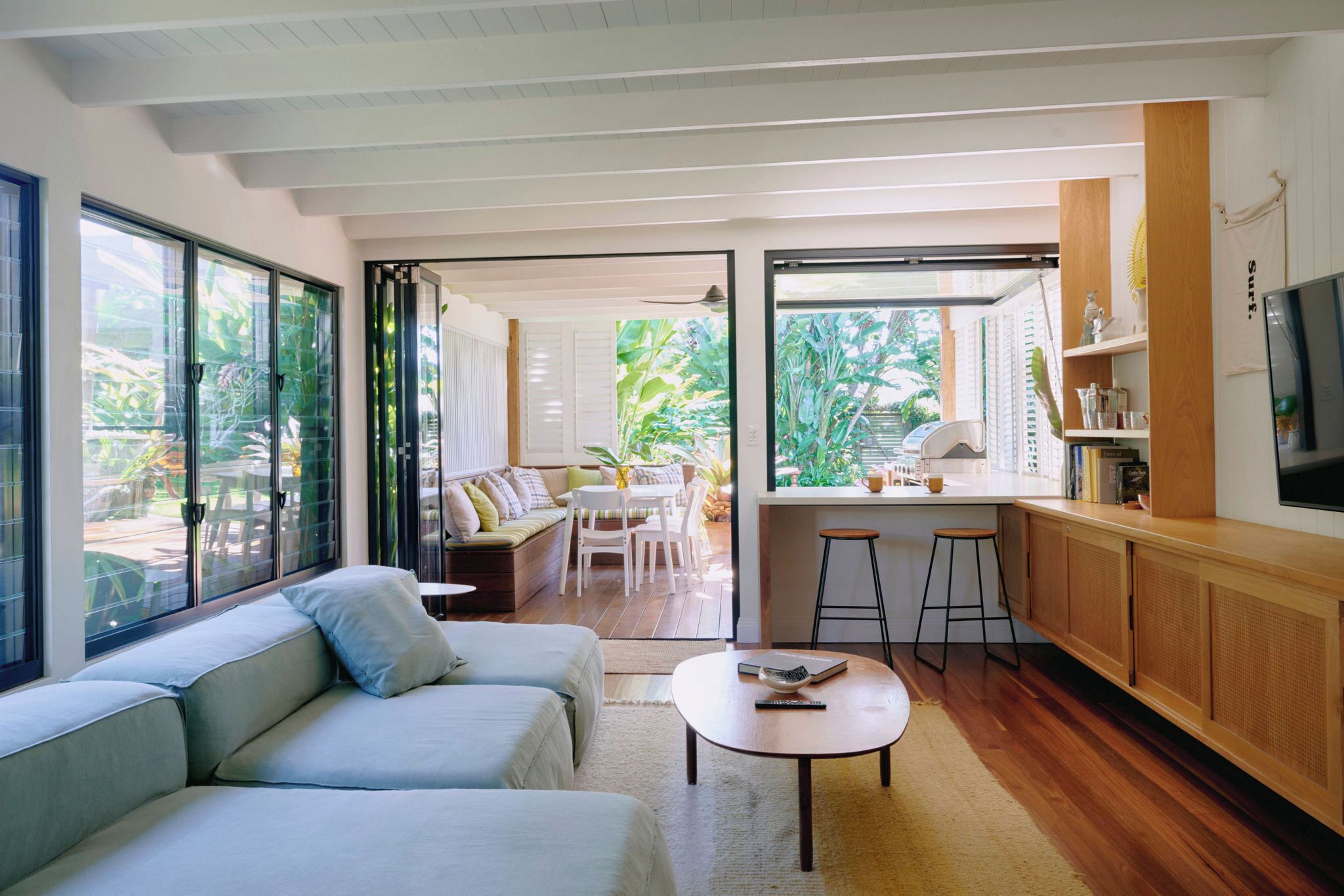 Una sala de estar moderna con un sofá, una mesita de centro y una zona de cocina con barra y taburetes.