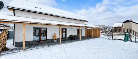 A snow-covered building with a covered porch and a green slide.