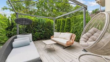 An outdoor patio with a covered seating area, a dining table, and a hanging chair.