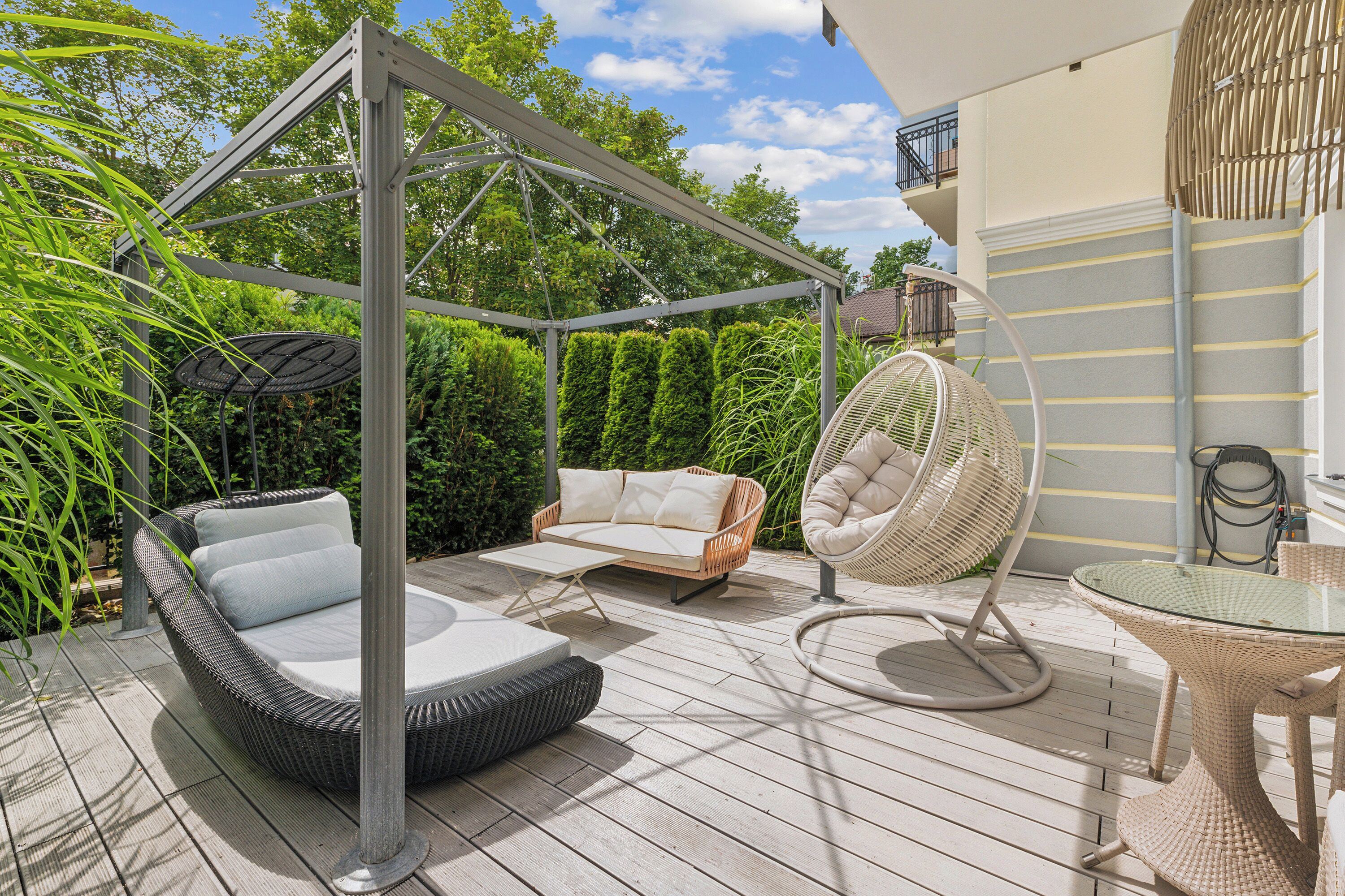 Eine Terrasse mit Schaukelstuhl, einer Sitzecke und einem Ventilator.