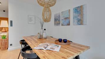 A dining area with a wooden table, chairs, a hanging light fixture, and wall art.