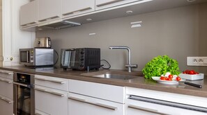 A modern kitchen with a microwave, toaster, and sink. - Parisian Opulence – Luxury Art Deco Apartment in Saint-Germain-des-Prés (Paris)
