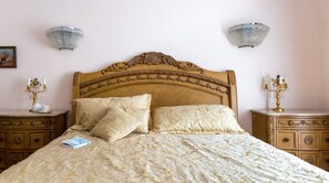 Una cama con cabecera decorativa, dos mesitas de noche con lámparas y un libro sobre la cama.