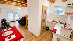 A modern kitchen with a wooden ceiling, a dining area with a red tablecloth, and a Christmas tree. - Apartment house, sauna and jacuzzi, Svätý Kríž 3 (Svätý Kríž)