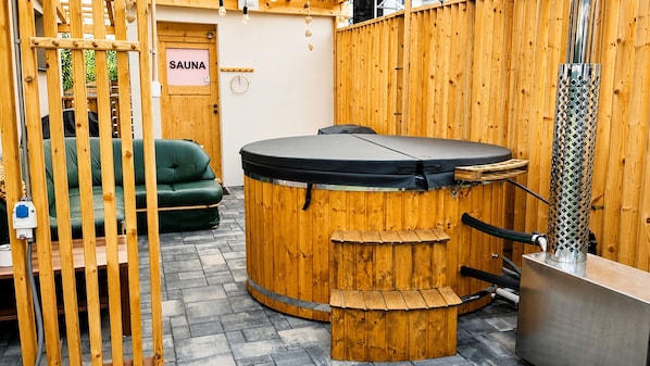 A sauna with a wooden exterior, a green sofa, and a sign labeled 'SAUNA'.