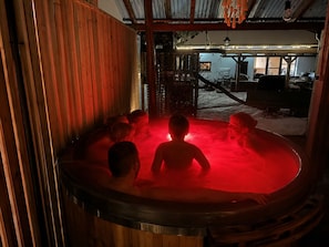 A hot tub with people inside, surrounded by wooden walls and a metal roof. - Apartment house, sauna and jacuzzi, Svätý Kríž 3 (Svätý Kríž)
