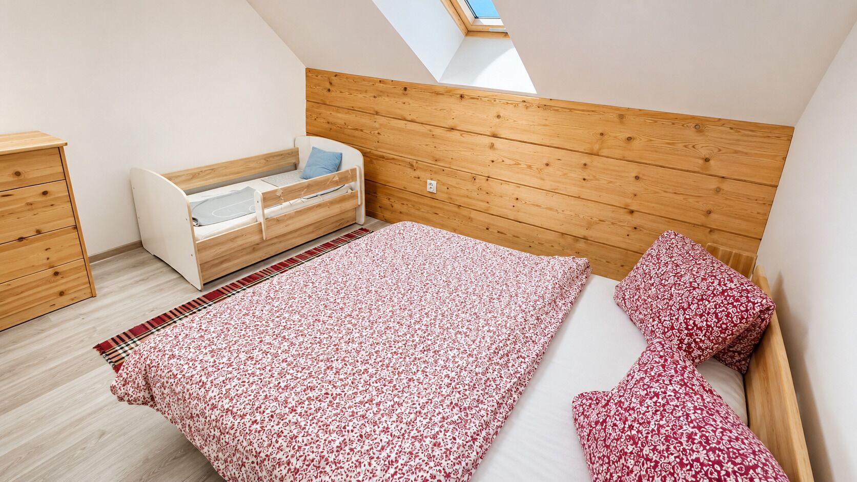 A bedroom with a bunk bed, a small desk, and a window.