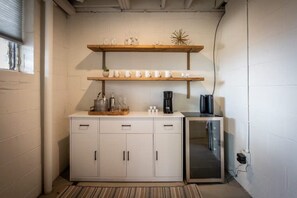 Une petite cuisine équipée d’un meuble blanc, d’une machine à café et d’un four à micro-ondes.
