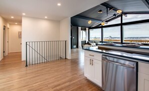 Une cuisine moderne avec vue sur la ville, un plancher en bois et un escalier menant à un niveau supérieur.