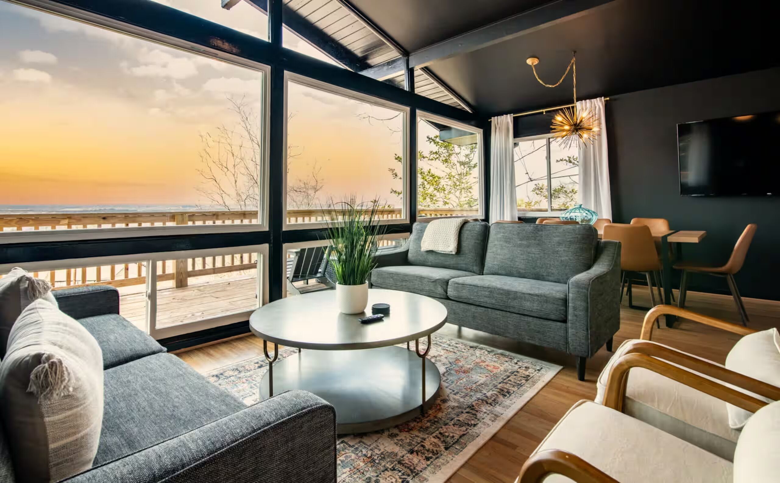 Un salon moderne avec vue sur l’océan, une table basse ronde et un grand téléviseur à écran plat.