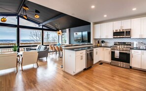 Une cuisine moderne avec vue, dotée d’appareils électroménagers en acier inoxydable, de meubles blancs et d’un coin repas offrant également une vue agréable.