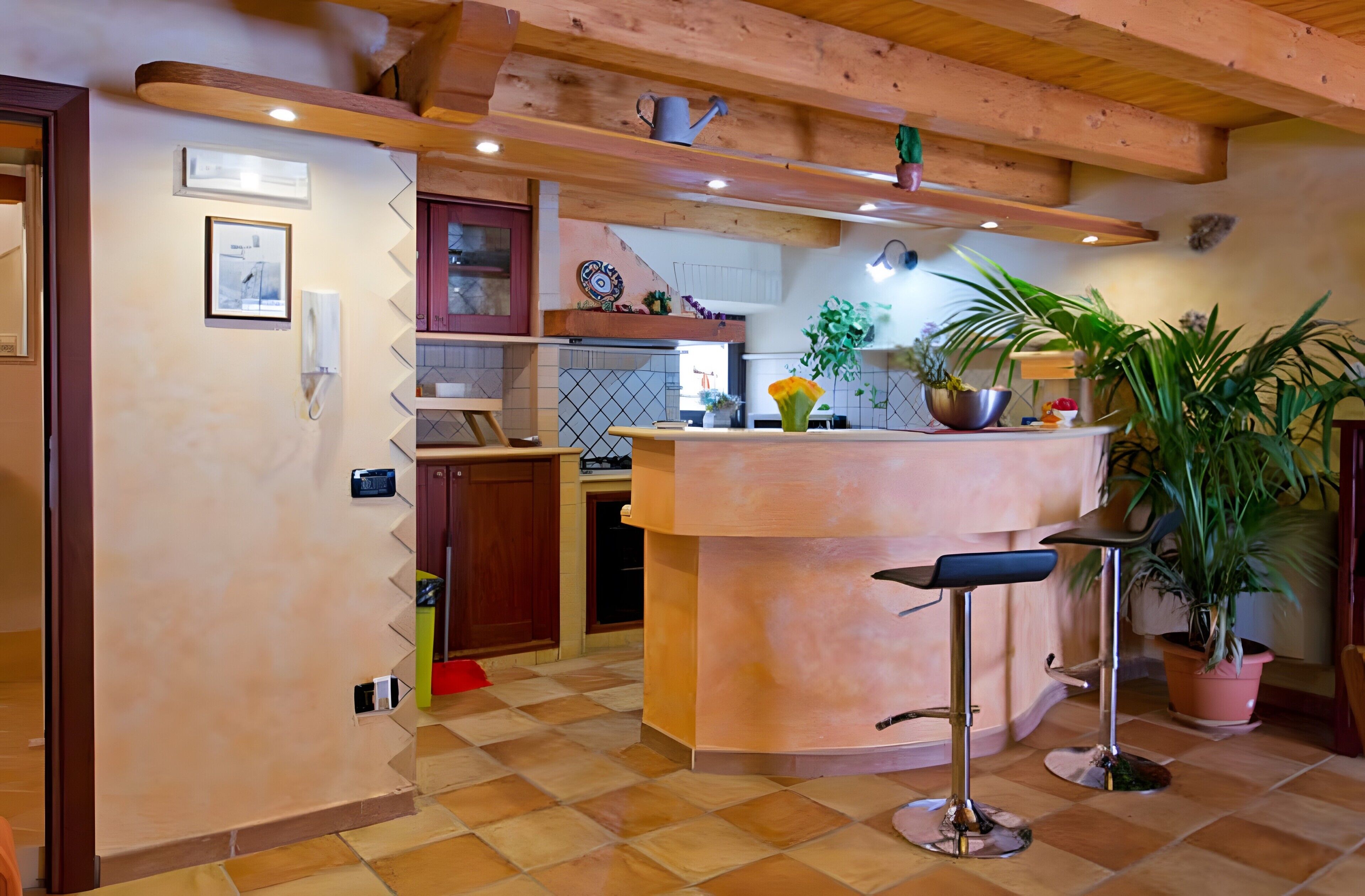Une cuisine dotée d’un îlot central, de poutres en bois, d’un revêtement de sol en carrelage et de divers appareils électroménagers.