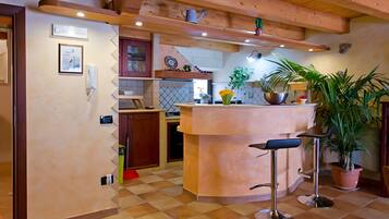 Une cuisine dotée d’un îlot central, de poutres en bois, d’un revêtement de sol en carrelage et de divers appareils électroménagers.