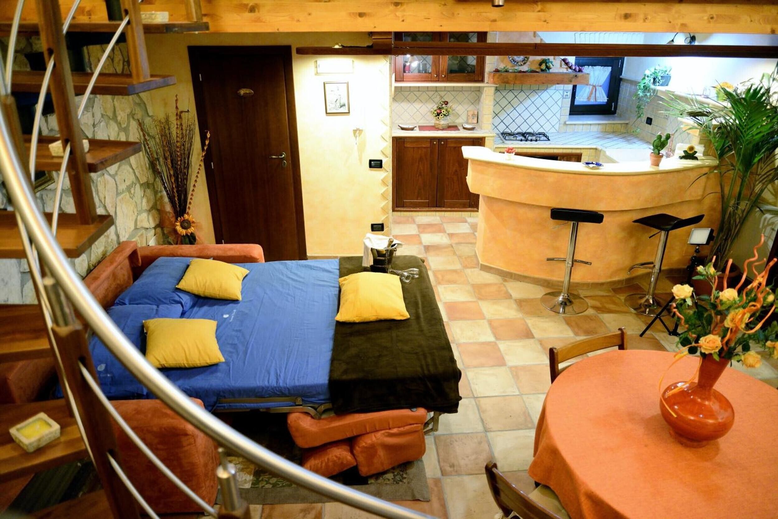 A compact hotel room with a bed, a small table, and a bar area.
