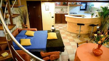 A compact hotel room with a bed, a small table, and a bar area.