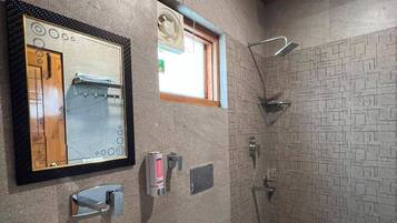 Een badkamer met een grote spiegel, een wastafel, toilet, douche en een raam.