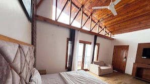 A bedroom with a large bed, a ceiling fan, and a TV.