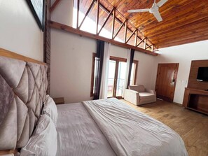 A bedroom with a large bed, a ceiling fan, and a TV.