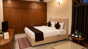 Quarto de hotel com cama, televisão, escrivaninha, sofá, mesa de centro e ventoinha no teto.