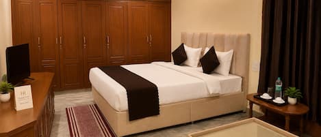 A hotel room with a bed, a TV, a desk, a sofa, a coffee table, and a ceiling fan.