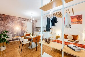 Ein moderner Wohnraum mit Essbereich, Küche und einem Bett mit Kopfteil.
